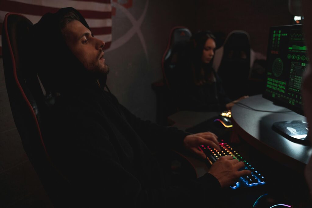 Young adults working on cybersecurity tasks in a dimly lit tech environment.
