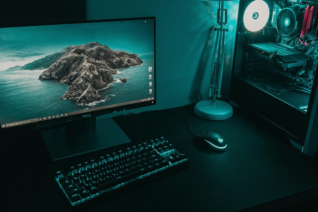 High angle of computer monitor with keyboard and mouse placed on table near CPU in dark workplace