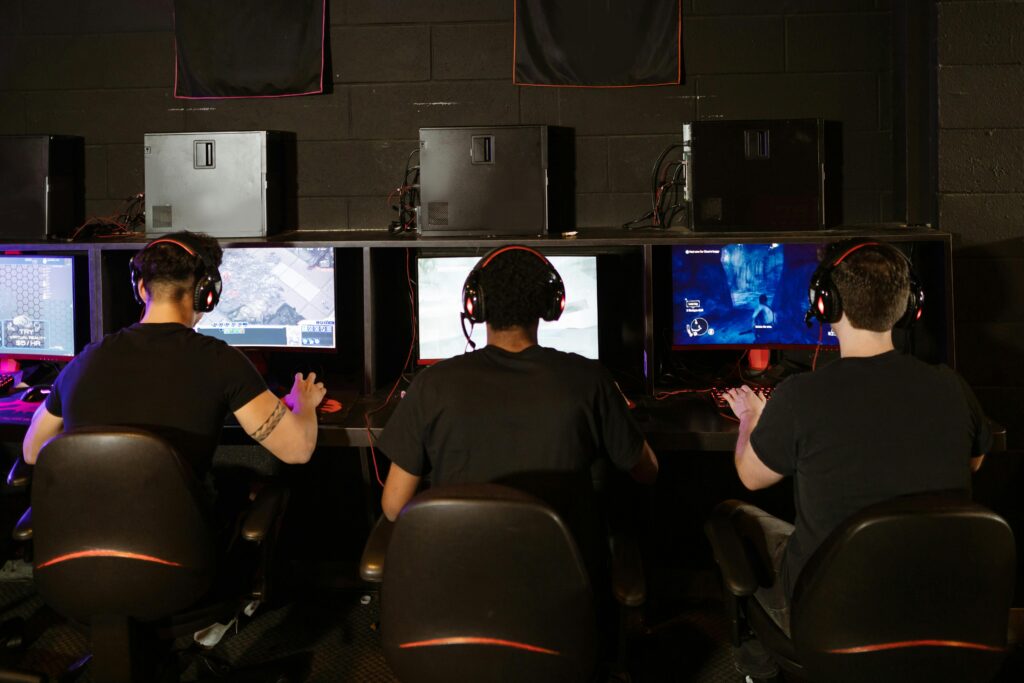 Three men focused on an intense PC gaming session in a modern esports arcade, enjoying teamwork and strategy.
