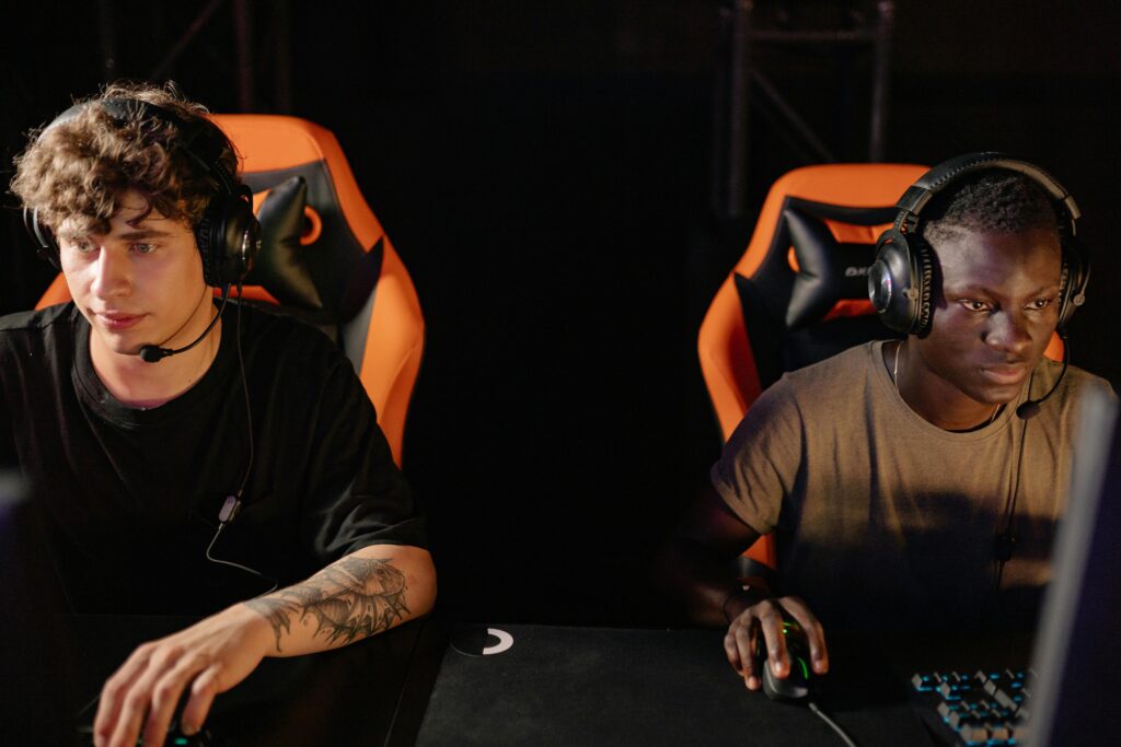 Two focused gamers wearing headsets in a cyber cafe, engaged in a competitive online match.
